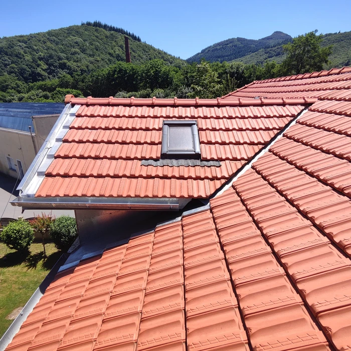 Terrasse extérieure couverte par une pergola bioclimatique à lames orientables en aluminium anthracite, fixée en applique sur façade enduit beige
