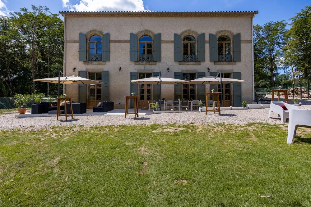 Maison individuelle contemporaine à deux étages, façade enduite blanche, toiture à faible pente avec débord en bois apparent, menuiseries noires aluminium, balcon filant