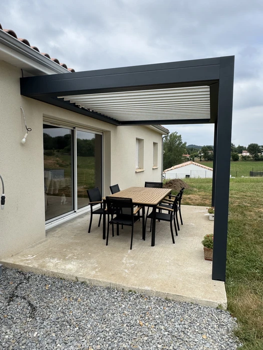 Terrasse extérieure avec pergola bioclimatique à lames orientables en aluminium anthracite, adossée à une maison contemporaine