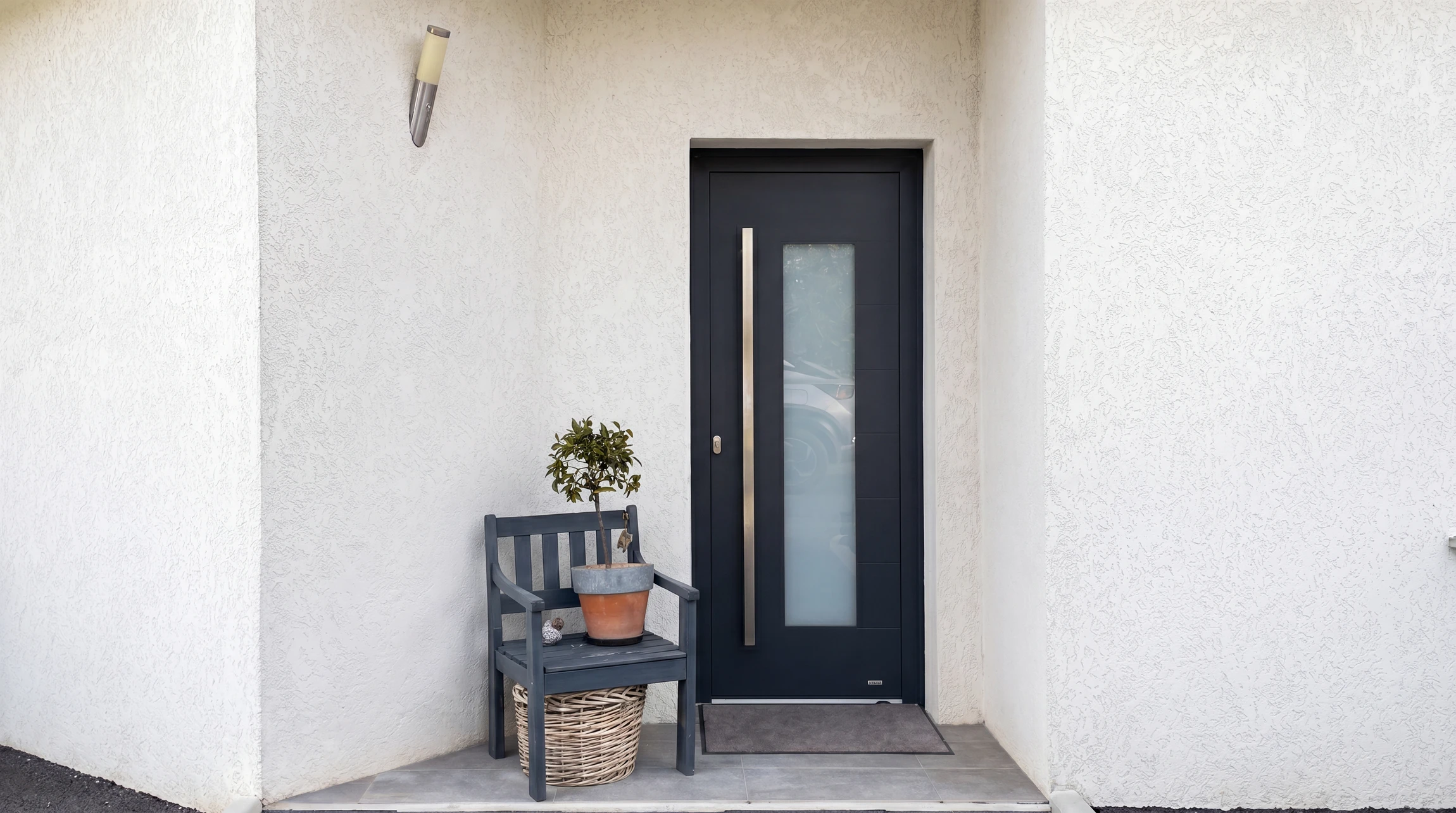 Entrée de maison moderne avec porte d'entrée anthracite à vitrage dépoli intégré et poignée longue en inox brossé