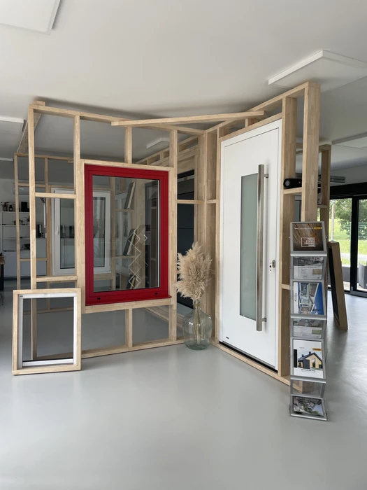 Façade extérieure rouge vif avec fenêtre double vantail en PVC blanc, encadrée d'un tableau et appui de fenêtre en enduit blanc