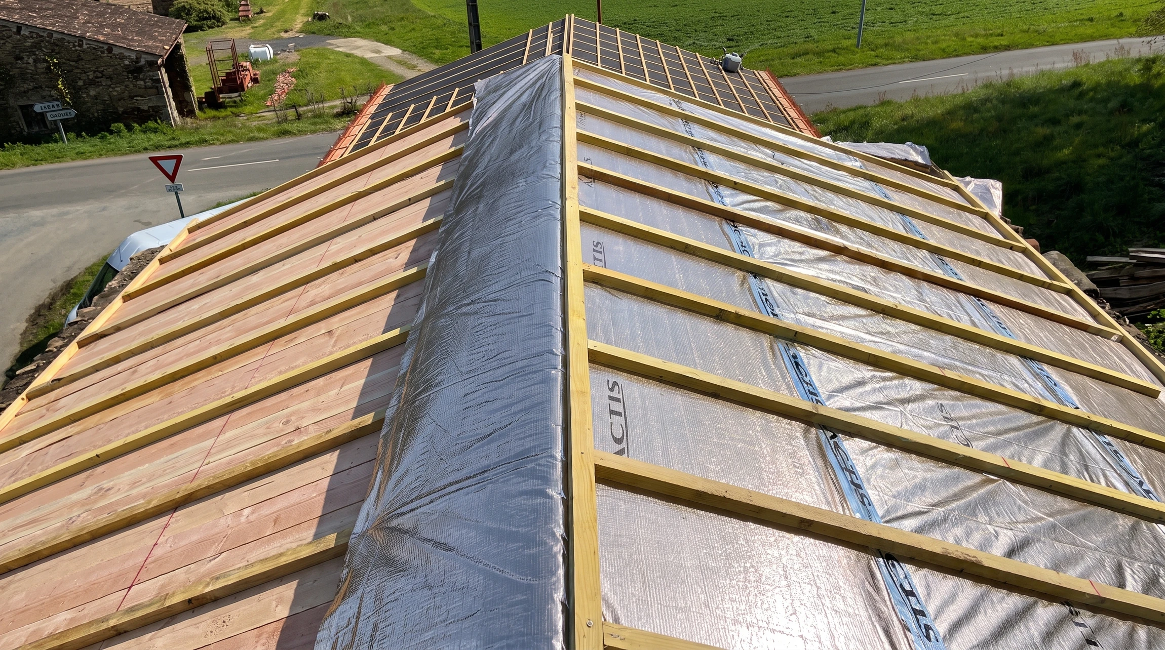 Chantier de construction résidentielle en cours, combles aménageables avec charpente bois apparente et isolation thermique jaune entre chevrons