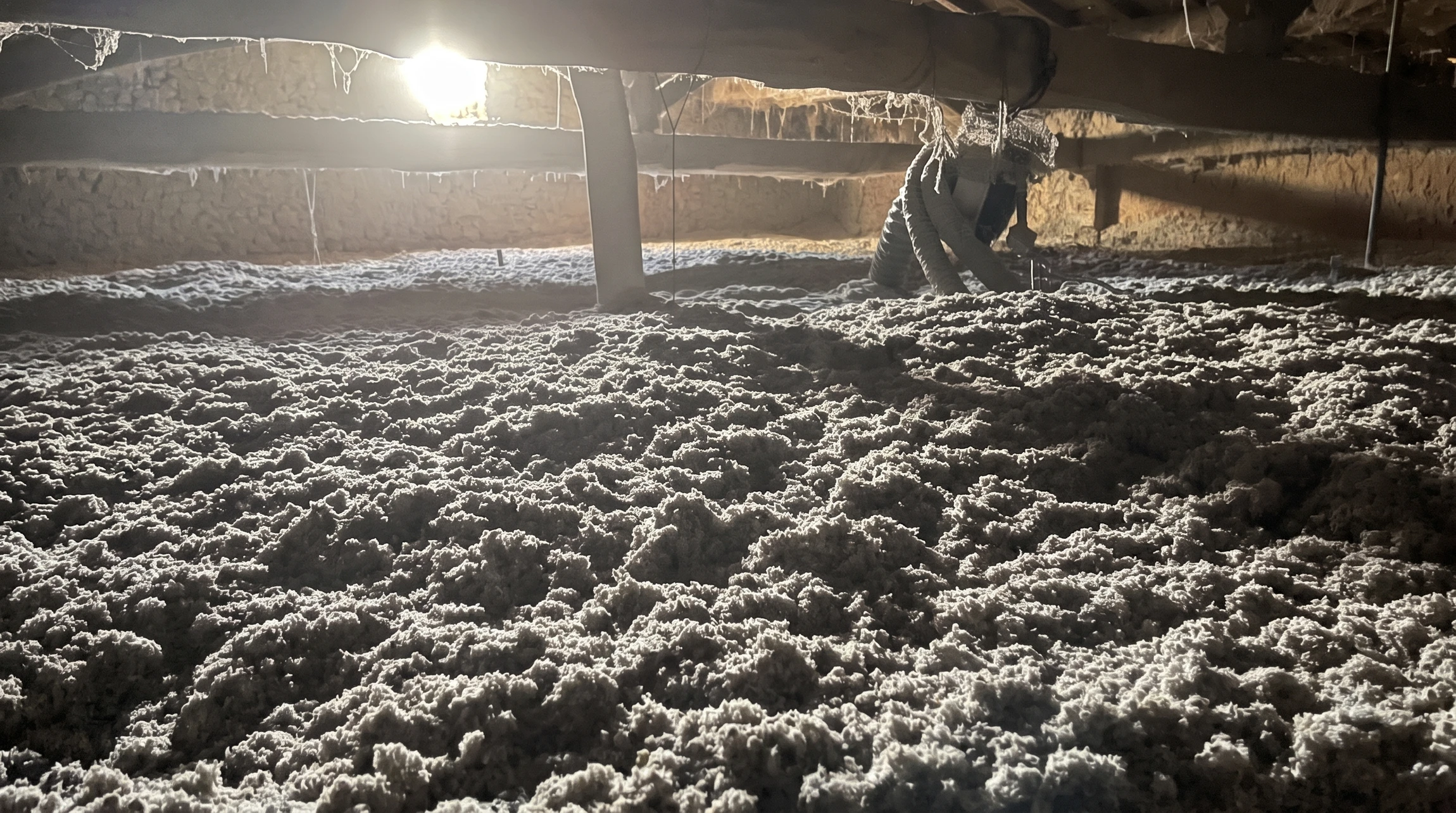 Ouvrier en équipement de protection individuelle installant de l'isolation thermique dans les combles d'une habitation